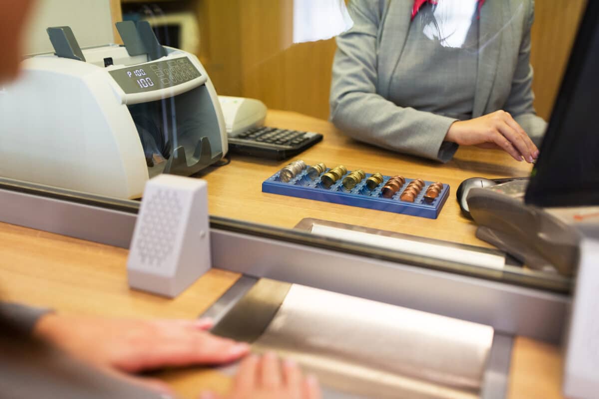 a teller protected by a thick glass barrier to show bank security